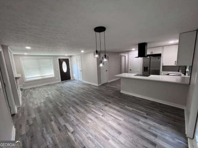 kitchen featuring dark wood-style floors, baseboards, a peninsula, stainless steel fridge with ice dispenser, and open floor plan