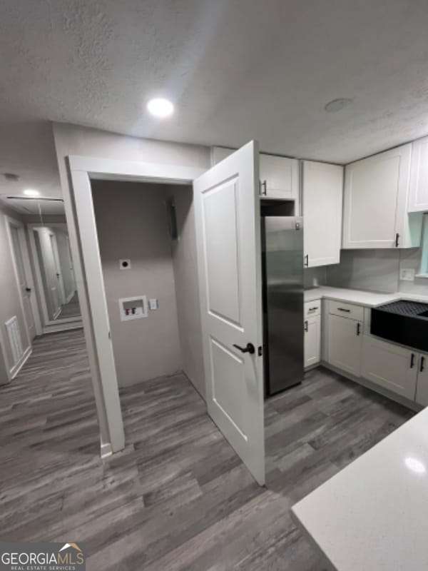 kitchen featuring white cabinetry, light countertops, freestanding refrigerator, dark wood-style floors, and a textured ceiling