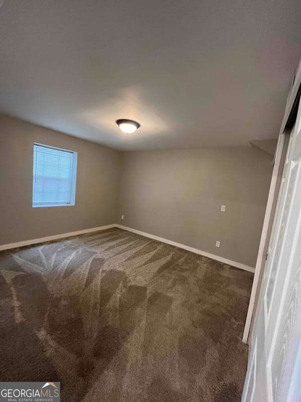 unfurnished bedroom with baseboards and dark colored carpet