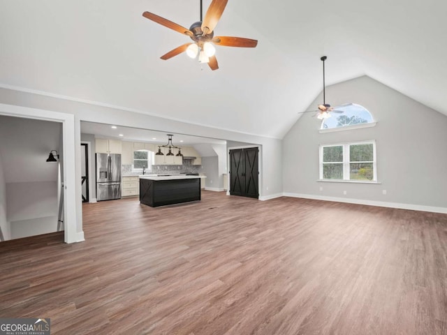 unfurnished living room featuring wood finished floors, a ceiling fan, baseboards, and high vaulted ceiling