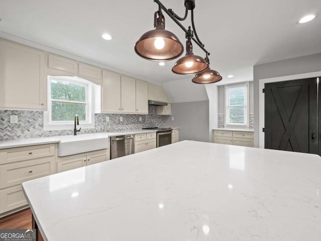 kitchen with a sink, stainless steel appliances, light stone counters, and backsplash