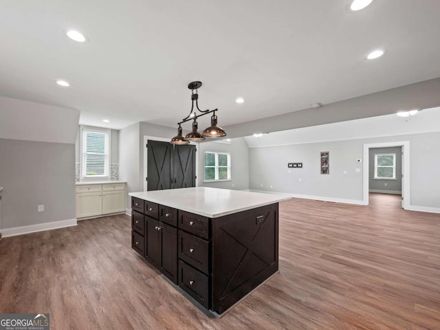 kitchen featuring baseboards, light wood finished floors, lofted ceiling, light countertops, and a wealth of natural light