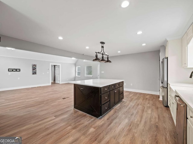 kitchen featuring appliances with stainless steel finishes, a kitchen island, light countertops, and light wood-style floors