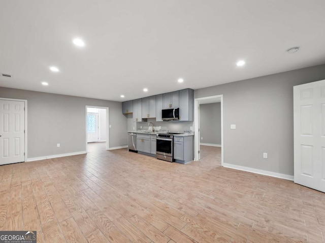 kitchen with stainless steel appliances, gray cabinetry, open floor plan, and light countertops