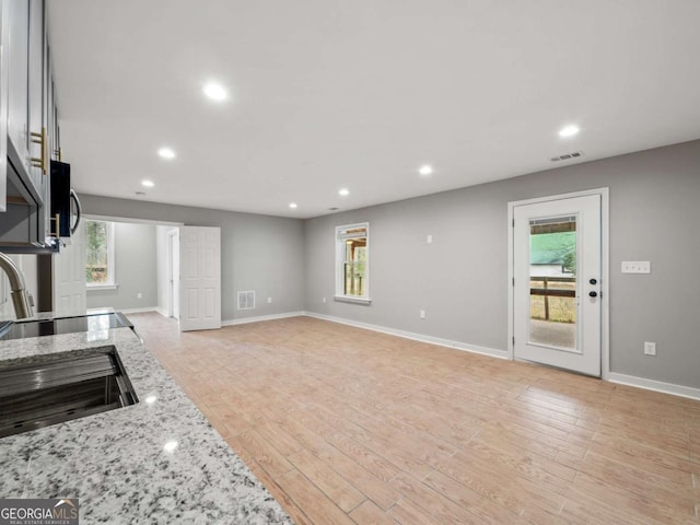 kitchen featuring light stone counters, visible vents, recessed lighting, stainless steel microwave, and light wood-type flooring