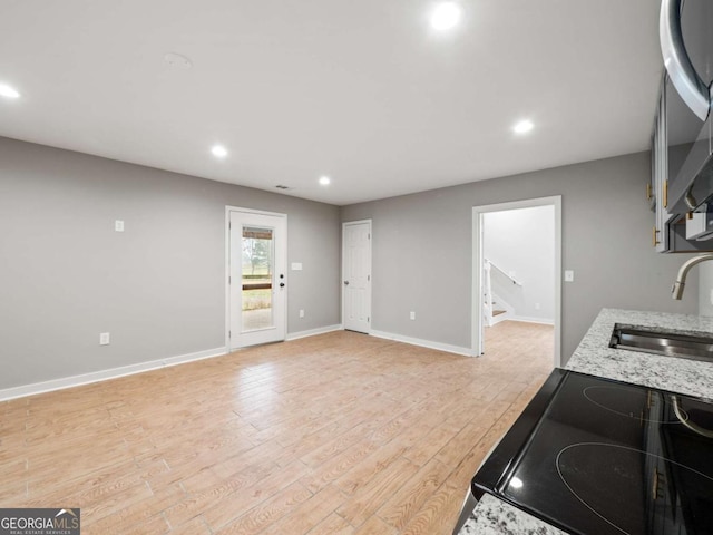 kitchen featuring a sink, light wood-type flooring, baseboards, and recessed lighting