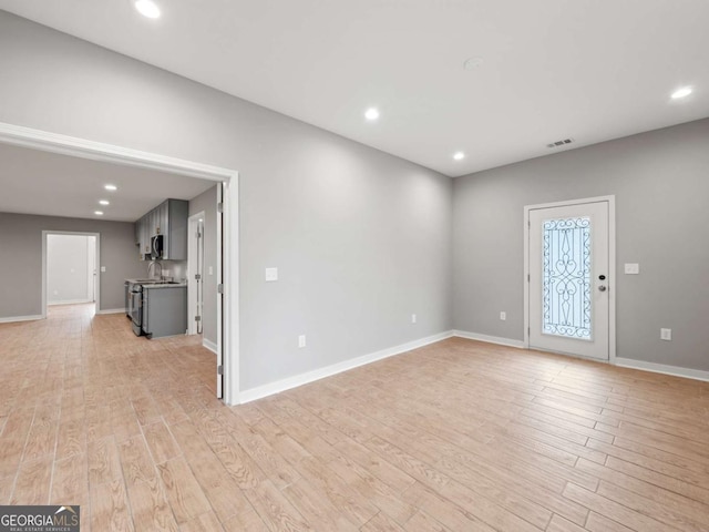 unfurnished living room featuring recessed lighting, baseboards, and light wood-style floors