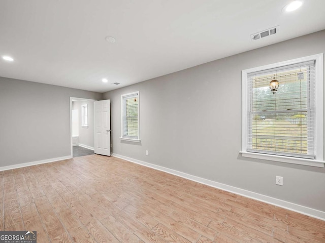 empty room featuring light wood-style flooring, recessed lighting, baseboards, and visible vents