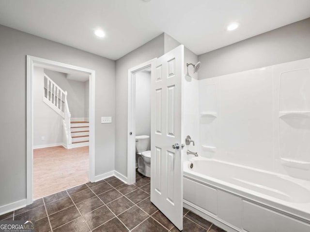 bathroom with tile patterned flooring, toilet, baseboards, and washtub / shower combination