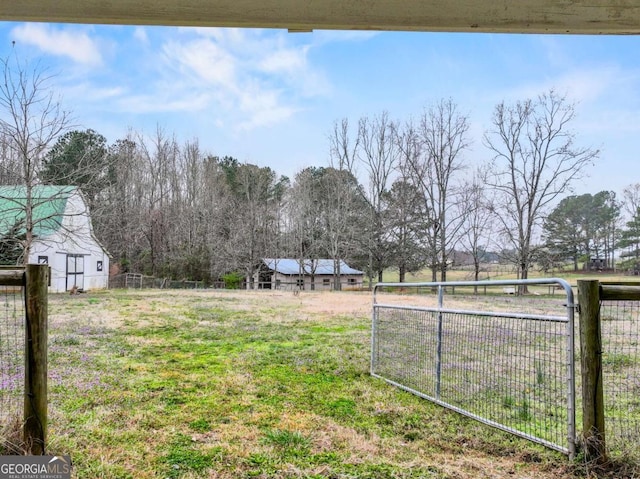 view of yard featuring a gate, a rural view, and fence