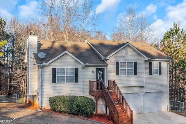 view of front of house with a chimney, concrete driveway, a garage, and fence