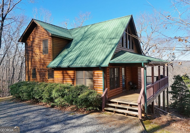 view of home's exterior featuring log veneer siding, a porch, and metal roof