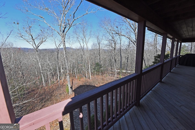 wooden terrace featuring a view of trees