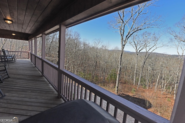 wooden terrace featuring a porch and a wooded view