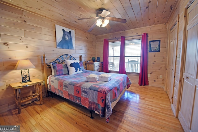 bedroom featuring light wood-style floors, wood ceiling, wood walls, and a ceiling fan