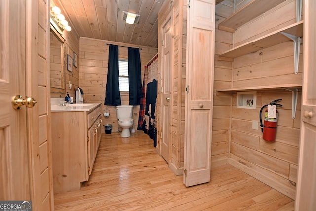 full bathroom featuring wooden walls, toilet, wood ceiling, wood finished floors, and vanity