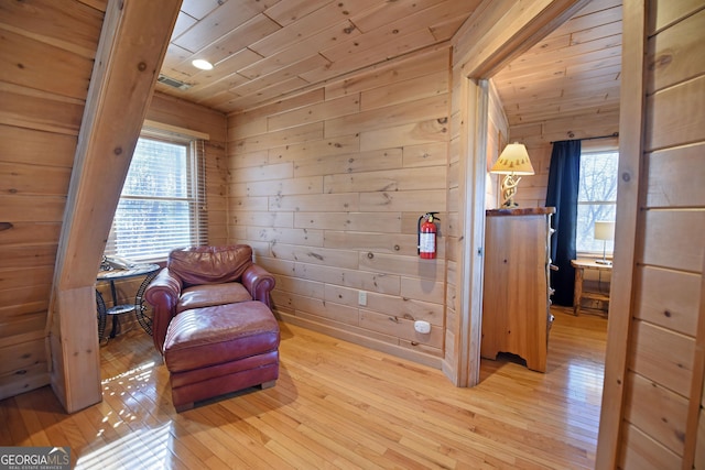 sitting room featuring wooden walls, wooden ceiling, and light wood finished floors