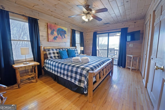 bedroom with access to exterior, visible vents, wood walls, wood ceiling, and hardwood / wood-style flooring