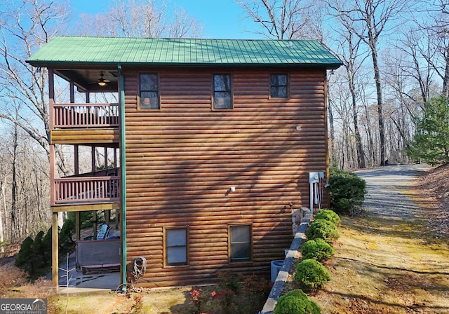 view of property exterior featuring ceiling fan, faux log siding, a balcony, and metal roof