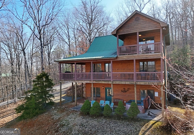 exterior space featuring faux log siding, metal roof, and a patio