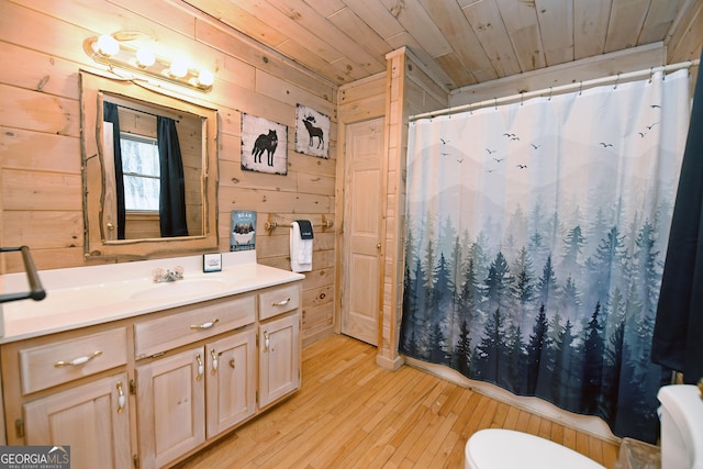 full bathroom featuring toilet, hardwood / wood-style floors, wooden walls, wood ceiling, and vanity