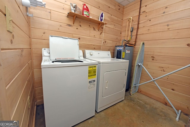 washroom featuring laundry area, wooden walls, washing machine and dryer, and water heater