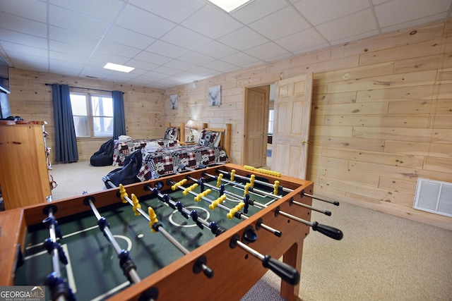 game room featuring a paneled ceiling, visible vents, carpet floors, and wood walls