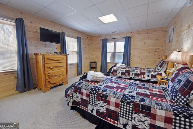 carpeted bedroom with wooden walls and a paneled ceiling