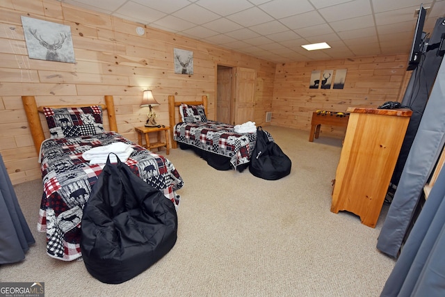 bedroom featuring a drop ceiling, wood walls, and carpet floors