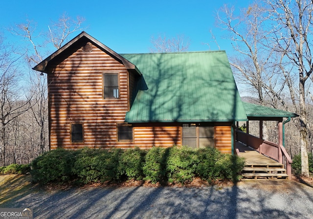 view of front of property with log veneer siding, a porch, and metal roof