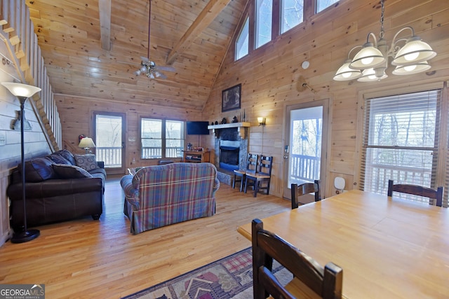 living room featuring an inviting chandelier, wooden walls, wood finished floors, and beam ceiling