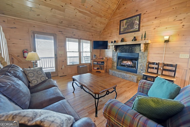 living room with high vaulted ceiling, hardwood / wood-style flooring, wooden ceiling, wood walls, and a fireplace