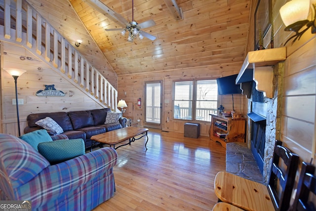 living room with wooden walls, a ceiling fan, high vaulted ceiling, light wood-style flooring, and wood ceiling