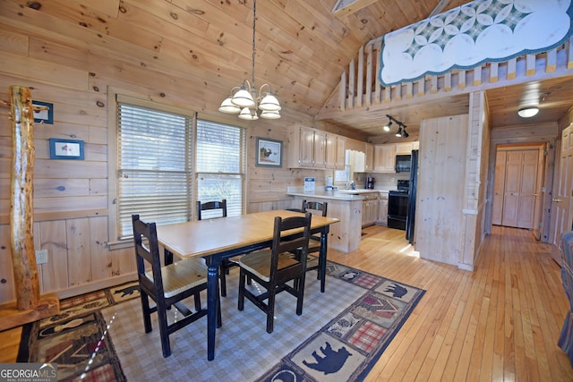 dining area featuring light wood-type flooring, wood walls, wooden ceiling, and a chandelier