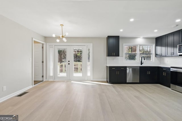 kitchen featuring light wood-type flooring, visible vents, stainless steel appliances, a chandelier, and dark cabinets