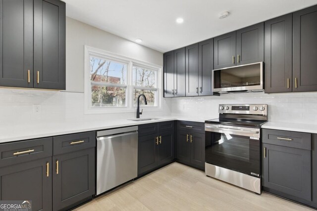 kitchen with a sink, tasteful backsplash, appliances with stainless steel finishes, and light countertops