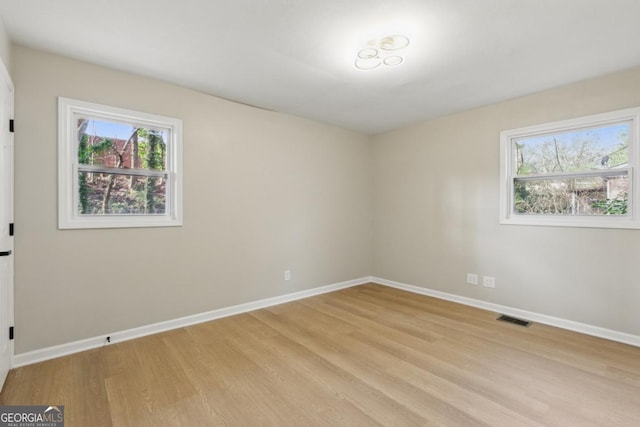 unfurnished room featuring visible vents, baseboards, and light wood-style floors