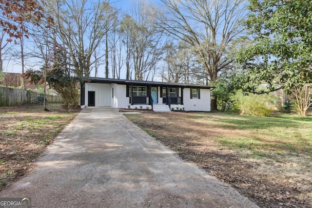 view of front of home with a front lawn, fence, covered porch, concrete driveway, and an attached carport