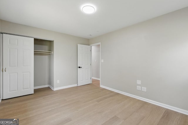 unfurnished bedroom with light wood-style flooring, baseboards, and a closet