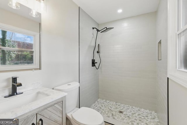 bathroom featuring vanity, toilet, recessed lighting, and tiled shower