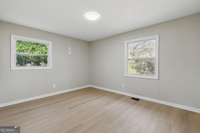 spare room featuring plenty of natural light, baseboards, and visible vents