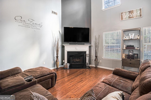 1921 Boulder Gate Dr, Ellenwood, GA 30294 - living room with visible vents, baseboards, a fireplace with flush hearth, a high ceiling, and wood finished floors