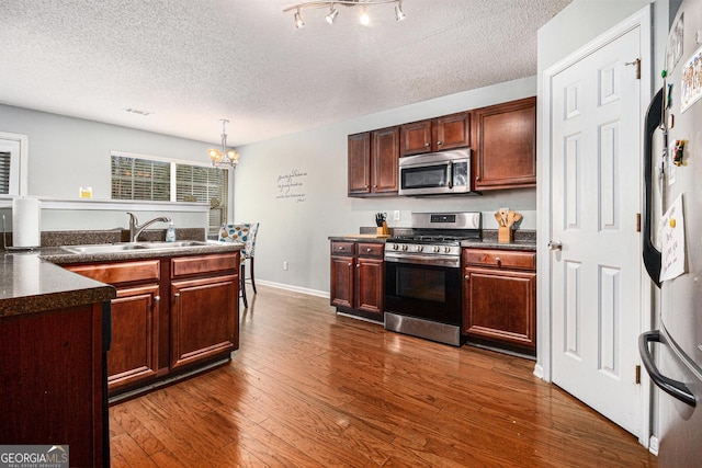 1921 Boulder Gate Dr, Ellenwood, GA 30294 - kitchen featuring dark countertops, a notable chandelier, appliances with stainless steel finishes, and a sink