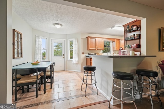 345 Lambeth Dr, Hiram, GA 30141 - kitchen featuring a breakfast bar area, light tile patterned flooring, baseboards, a textured ceiling, and a peninsula
