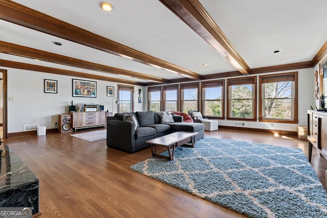 living area with beamed ceiling, wood finished floors, and visible vents