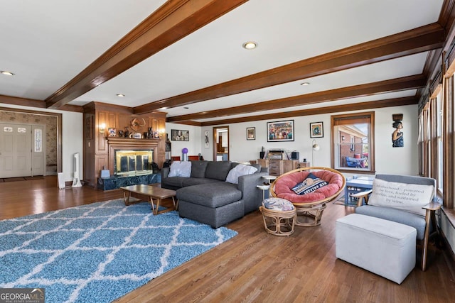 living area featuring beam ceiling, wood finished floors, a high end fireplace, and ornamental molding