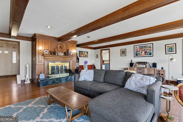 living area featuring beamed ceiling, wood finished floors, baseboards, and a premium fireplace