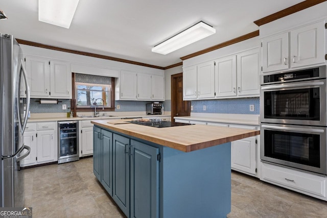 kitchen with a sink, stainless steel appliances, wine cooler, white cabinets, and wooden counters