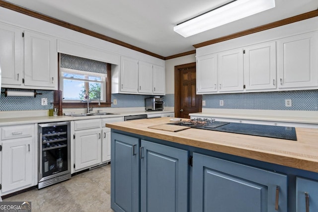 kitchen with crown molding, wine cooler, butcher block countertops, white cabinetry, and a sink