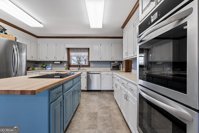 kitchen featuring blue cabinetry, stainless steel appliances, butcher block counters, and white cabinetry